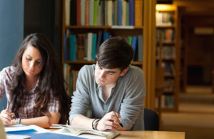 Mädchen und Junge lernen in der Bibliothek gemeinsam.