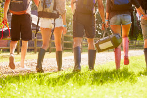 Beine von Jugendlichen, sie laufen mit Gummistiefeln durchs Gras