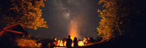 zwei Jugendliche sitzen vor einem Lagerfeuer unterm Sternenhimmel